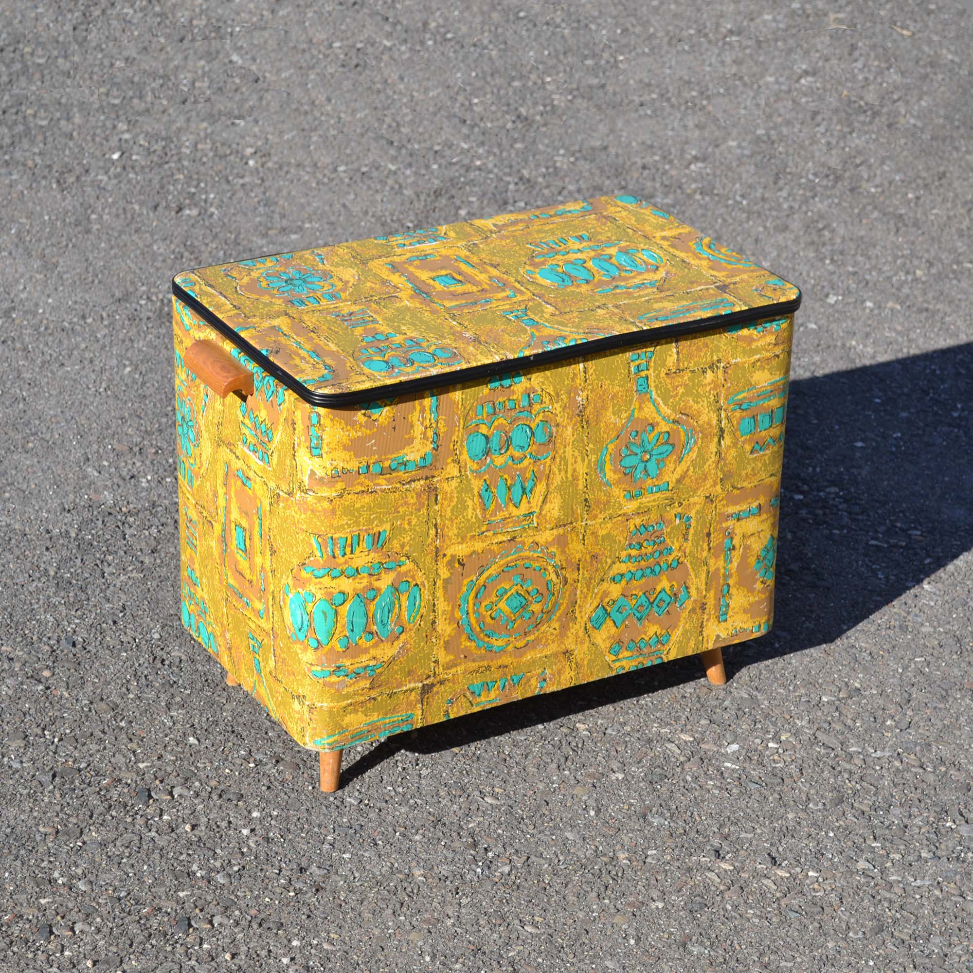 Coffre à jouets des années 1960, avec habillage en vinyle imprimé décor sixties. Avec couvercle pivotant. couleur moutarde et turquoise.