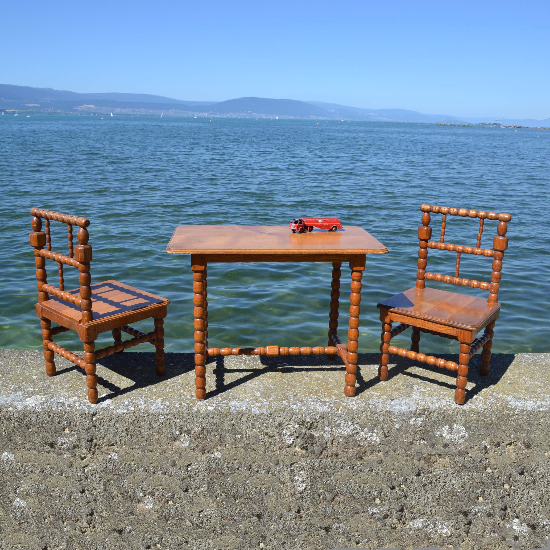 Mobilier d’enfant, de fabrication artisanale des années 1960. Par un ébéniste. avec les pieds réalisés au tour à bois. Table + 2 chaises.