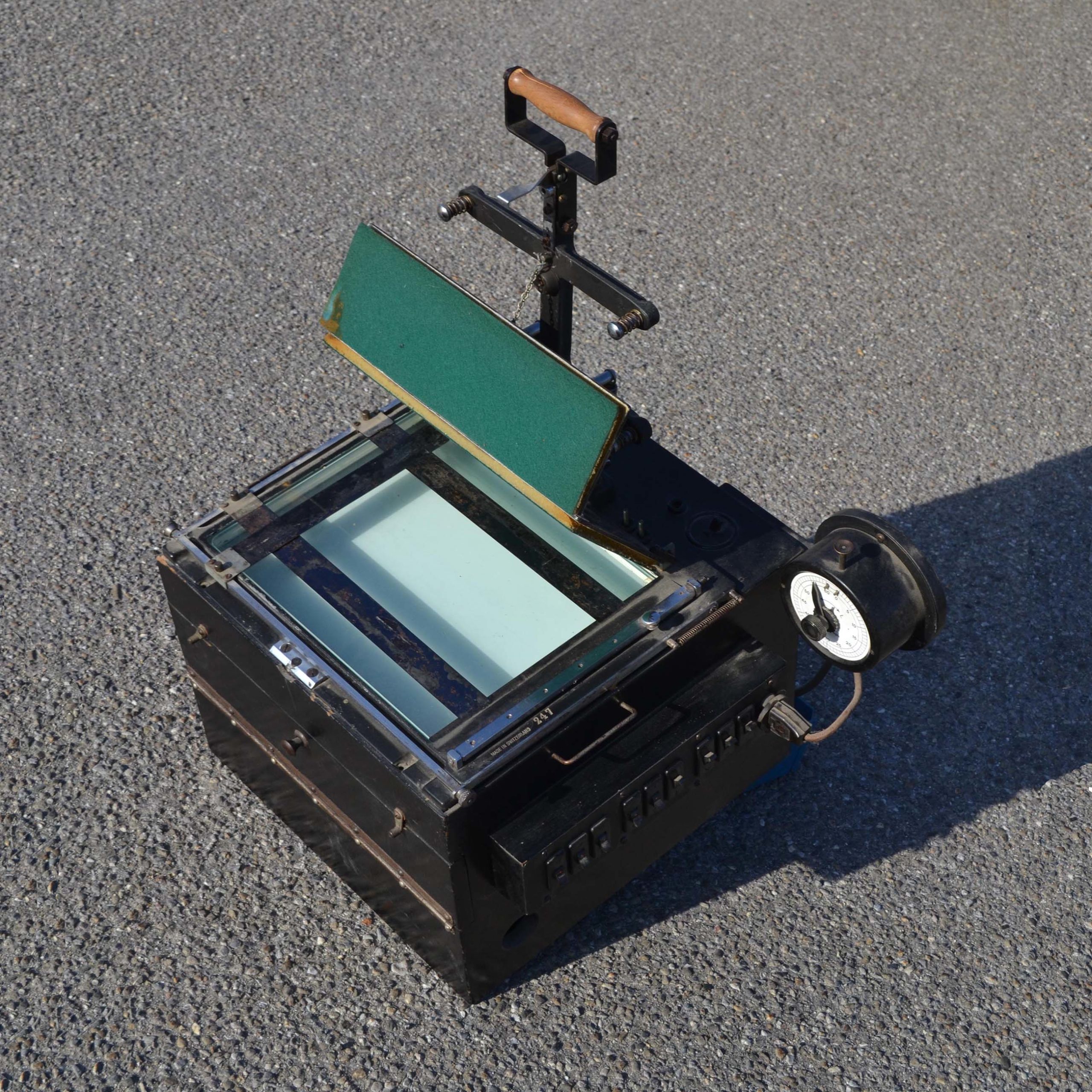 Curieuse machine: Il doit s’agir dune sorte de tireuse pour les photos argentiques. Pour exposer les négatifs, ou alors développement