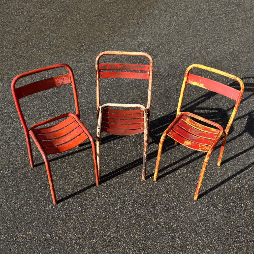 3 chaises de terrasses de bistrot dépareillées. Probablement de marque Tolix, type T1 et T2, (une ou 2 lattes sur le dossier). En état d’origine