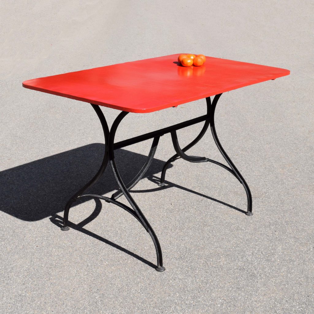 Table de jardin ancienne en fer, de fabrication Suisse, d’avant guerre. Piétement en fer T cintré. J’ai repeint le plateau en rouge