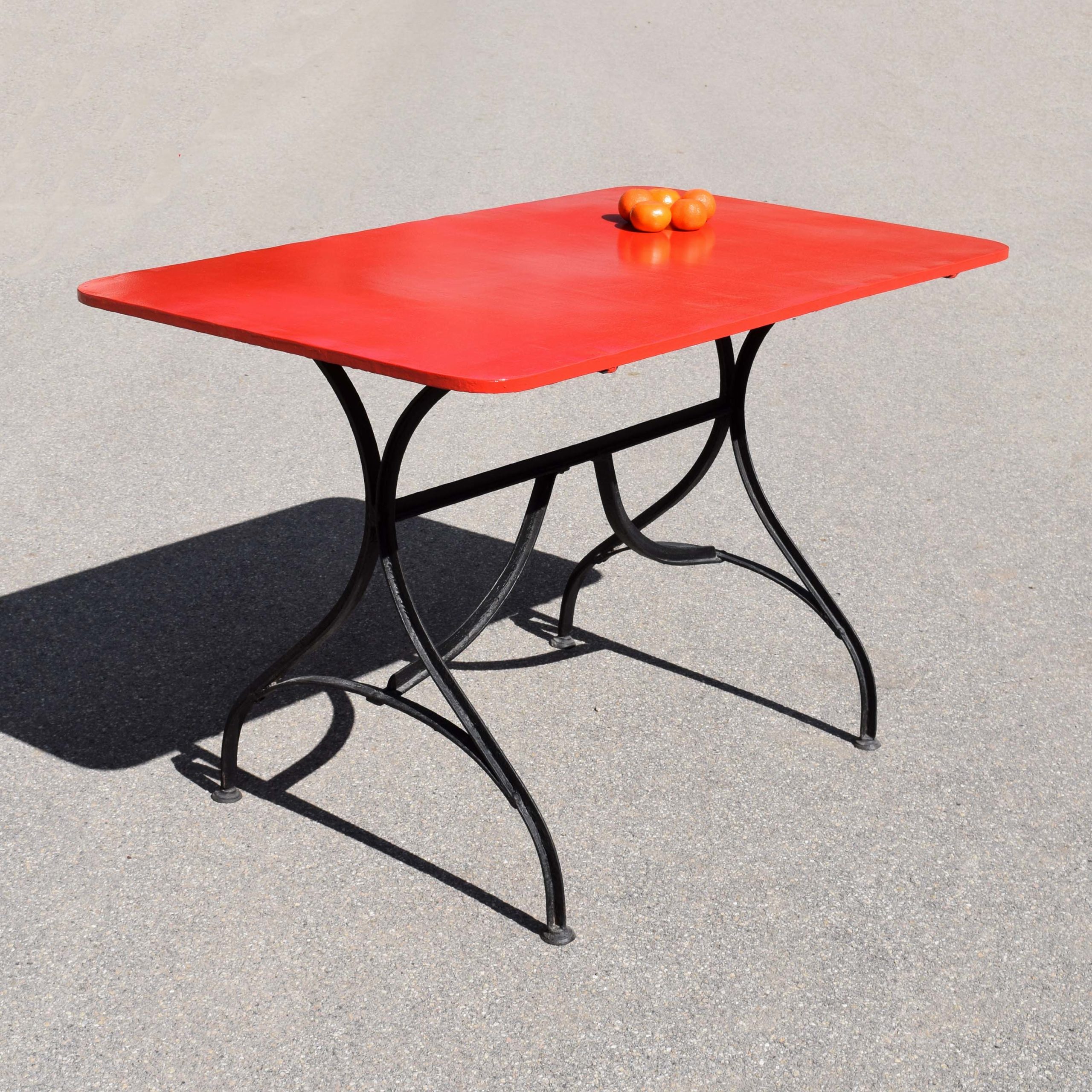 Table de jardin ancienne en fer, de fabrication Suisse, d’avant guerre. Piétement en fer T cintré. J’ai repeint le plateau en rouge