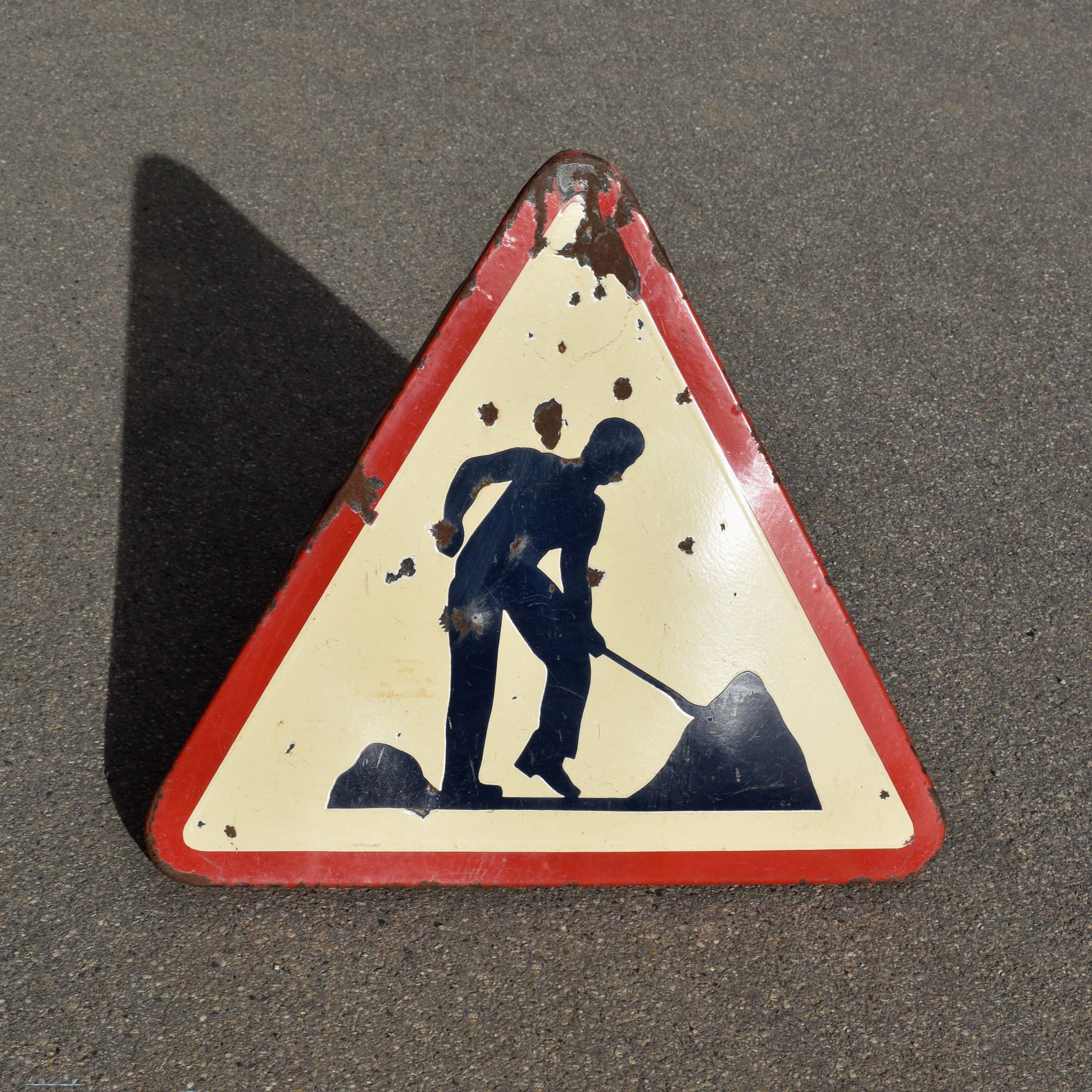 Triangle de danger pour signaler des travaux / un chantier. Daté 1967. En tôle émaillée. Avec pictogramme d'un ouvrier avec sa pelle.