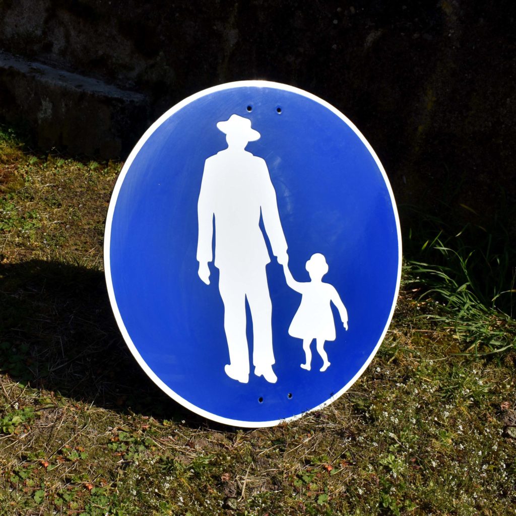 Panneau pour indiquer un chemin pour les piétons. Avec pictogramme homme au chapeau et fillette. En tôle émaillée, peut-être d’origine Allemande.