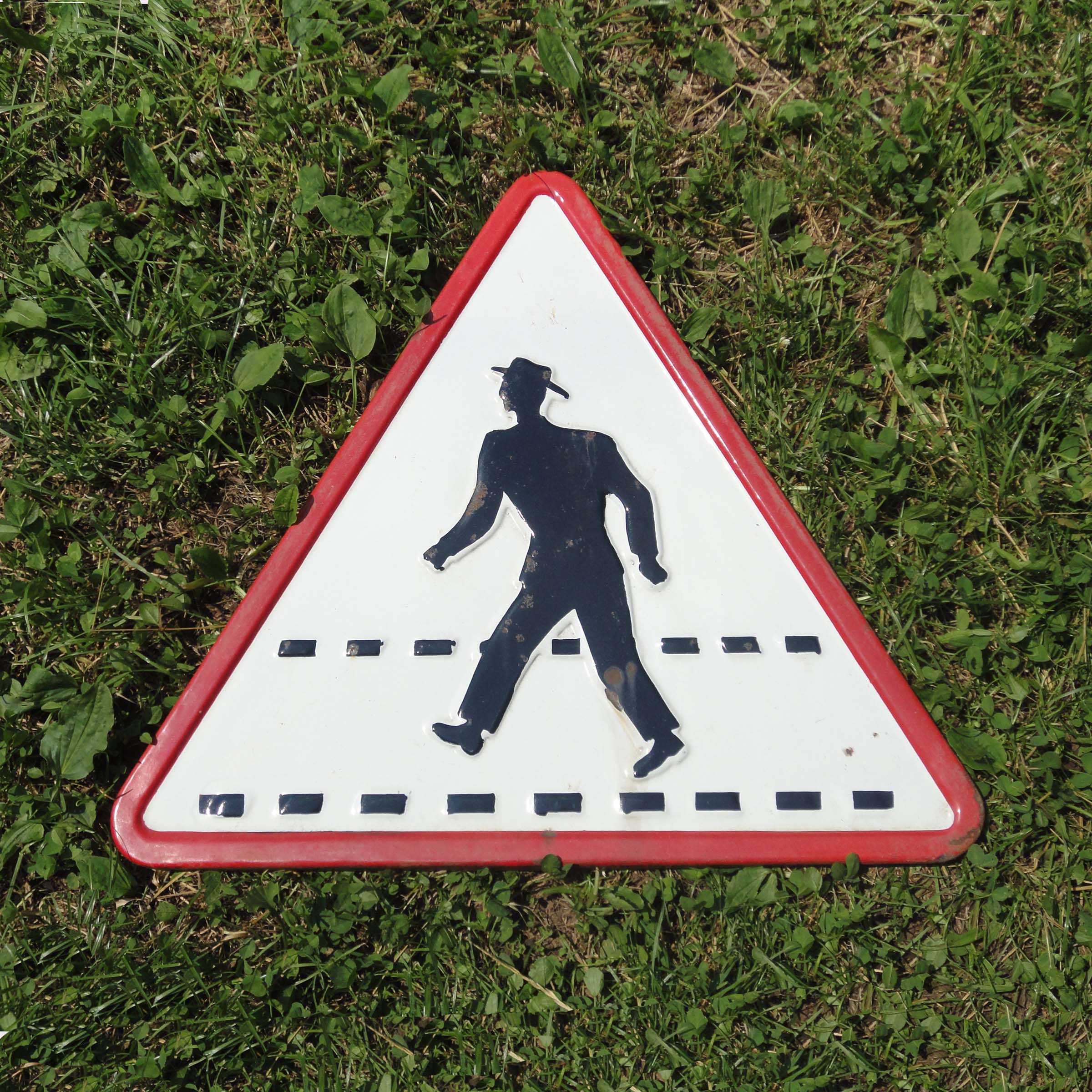 Panneau de signalisation d’origine française. Pour indiquer une traversée piétons. Avec pictogramme d’un homme au chapeau