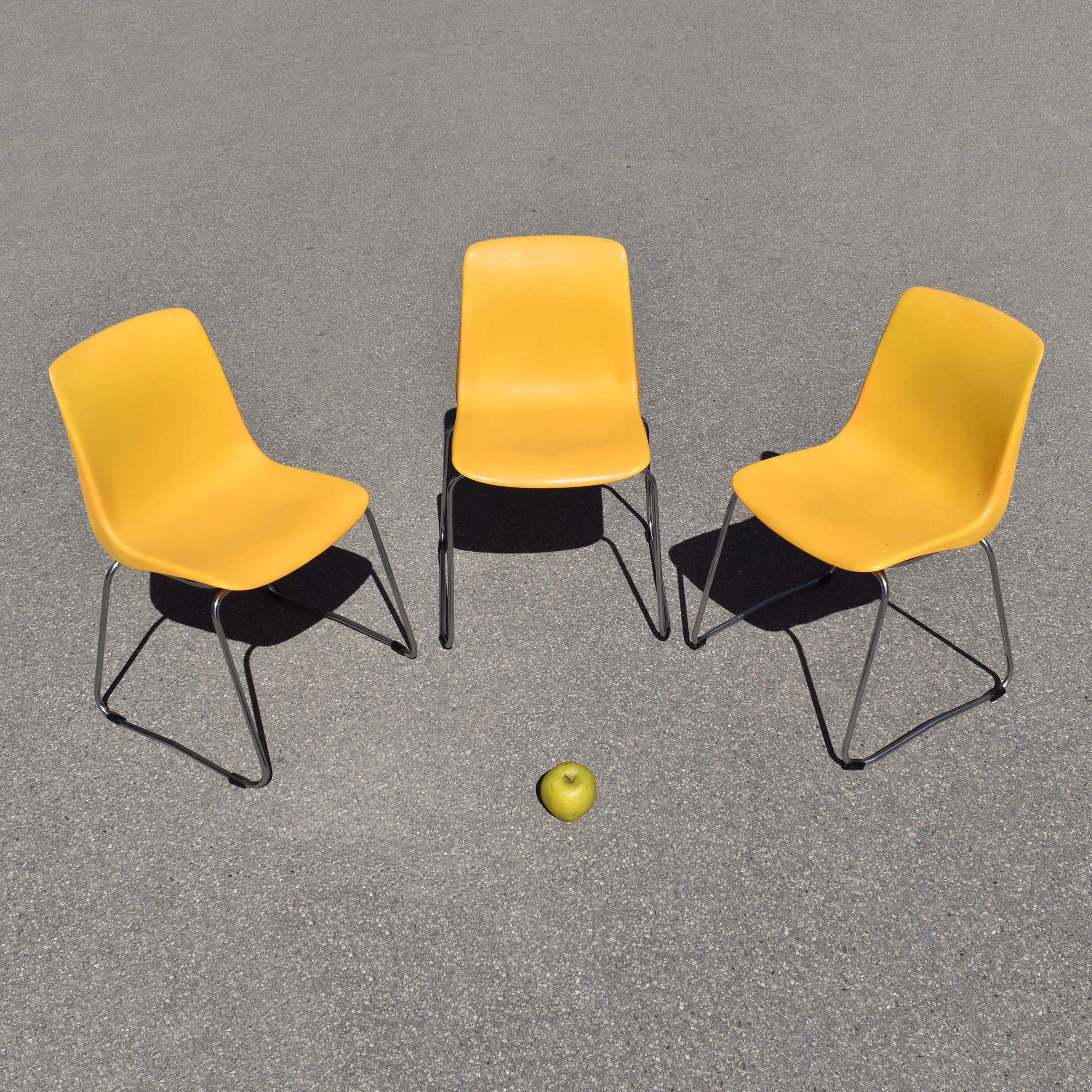 3 chaises en plastique vintage Grosfilex coques style Robin Day. Assises monbloc en plastique moulé jaune et piètement en fil acier chromé. Vintage seventies.