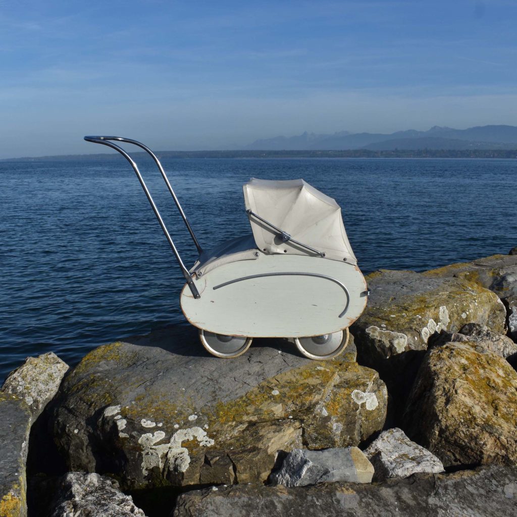 Poussette Helvétia beige des années 1950, avec caisse en bois. Petit modèle pour poupée, avec capote pliante, habillage en toile cirée banche.