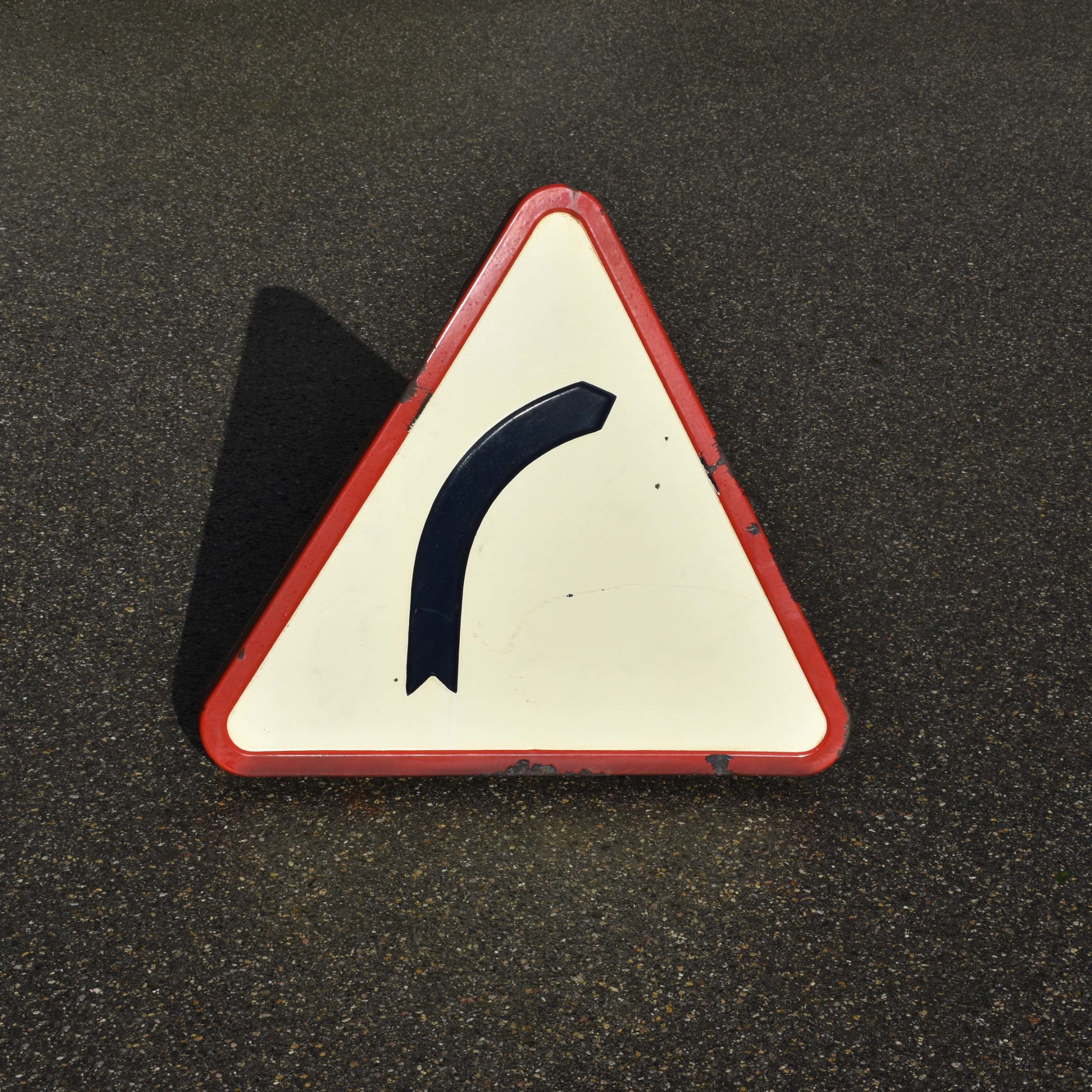 Panneau de signalisation routière en tôle émaillée, en relief. Triangulaire, attention au virage, daté de 1958.