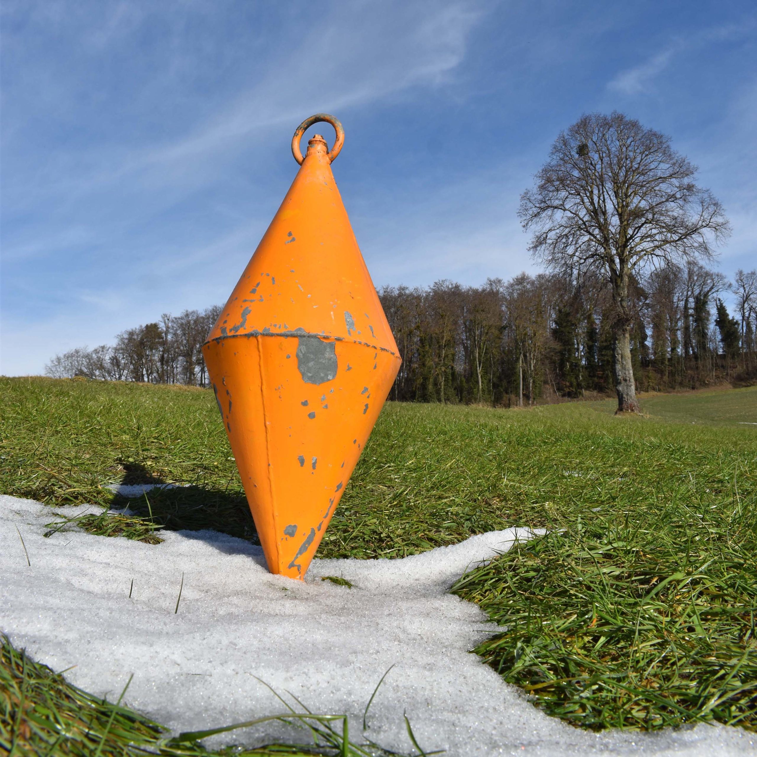 Vieille bouée d’amarrage de bateau en fer, dite “corps mort”. De forme losange, en tôle acier zinguée, et peinte en orange.
