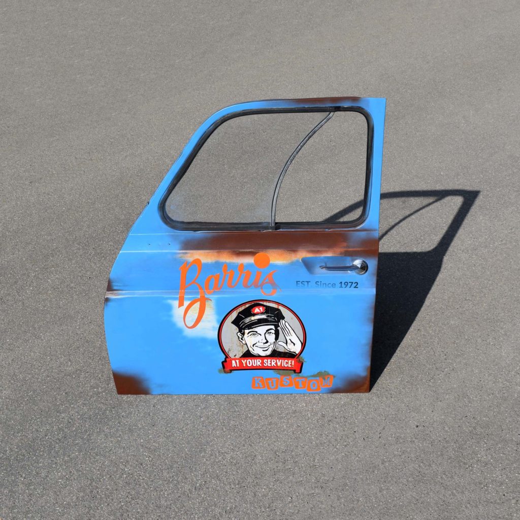 Porte avant de Renault 4L. Qui a été décorée avec des stickers, et patinée façon “route 66”. Idéal comme déco garage vintage.