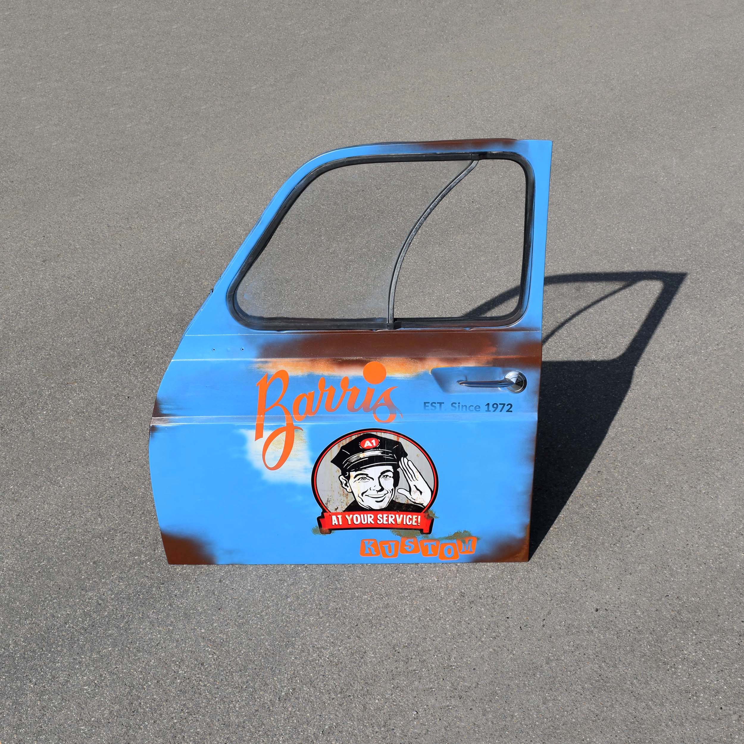 Porte avant de Renault 4L. Qui a été décorée avec des stickers, et patinée façon “route 66”. Idéal comme déco garage vintage.