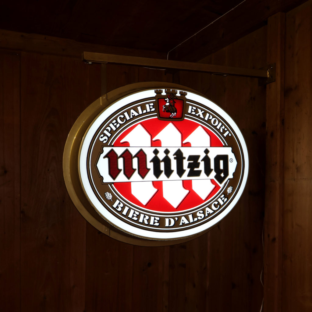 Mützig enseigne lumineuse ovale en potence pour la bière Alsacienne Mützig. Avec le logo vers 1977