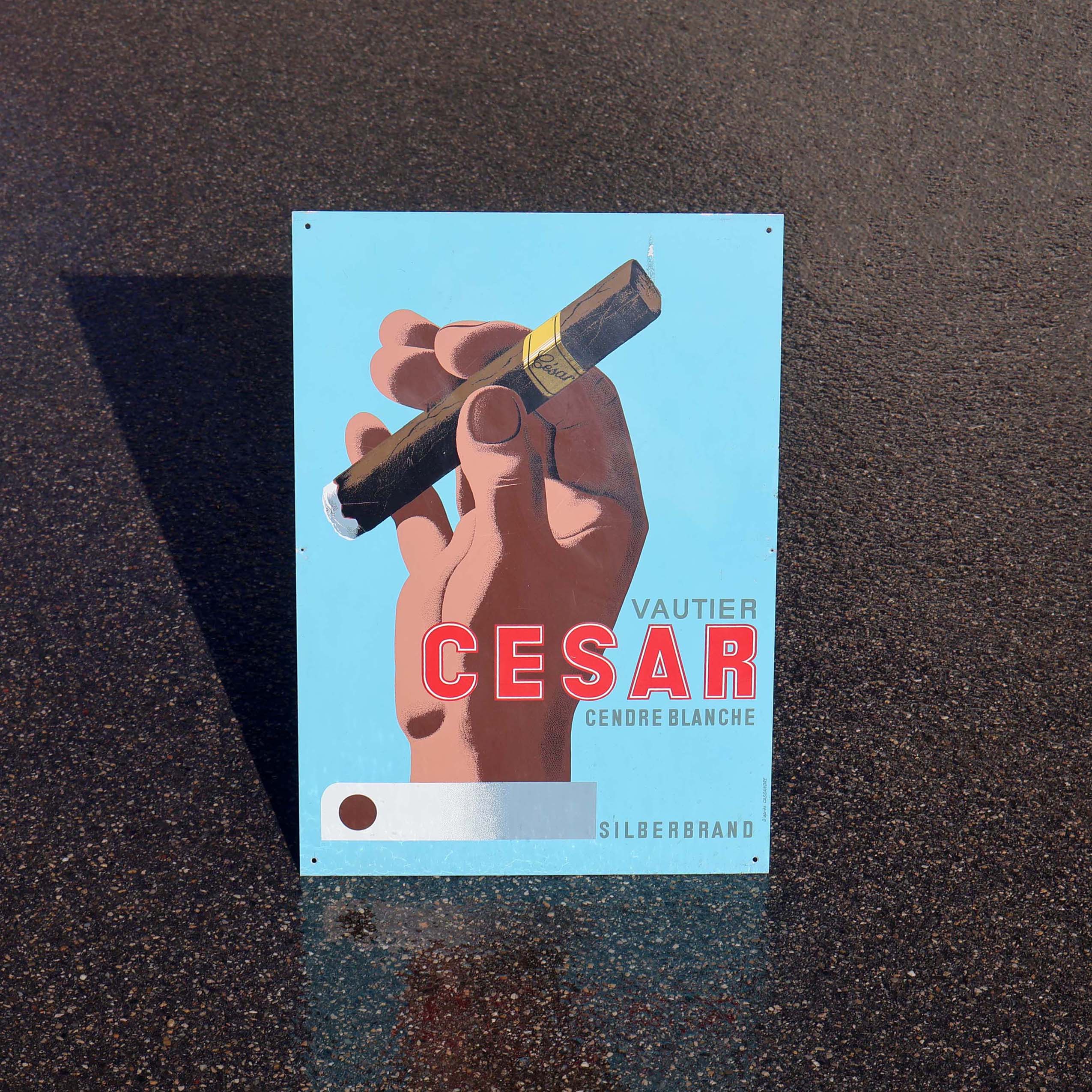 Tôle imprimée publicitaire. Pour les cigares César de Vautier. Illustration d'une main qui tient un cigare. D'après une affiche de Cassandre.